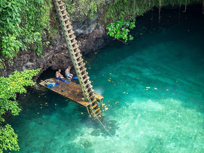 A close up of people sitting on the deck at the bottom of To Sua Ocean Trench, Samoa.